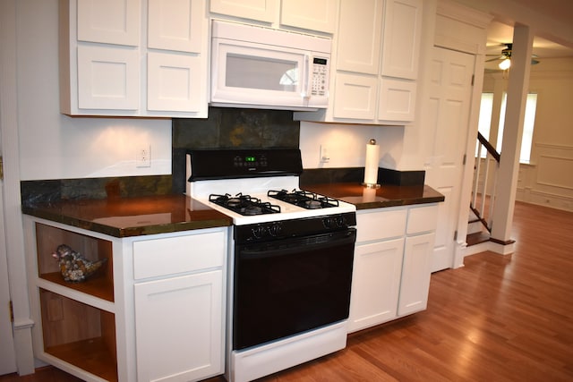 1131 Emmet St, Petoskey, MI 49770 - kitchen with white microwave, gas stove, wood finished floors, white cabinetry, and dark countertops