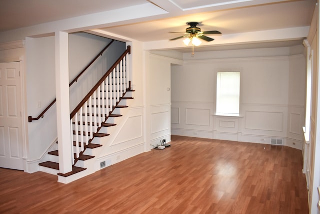 1131 Emmet St, Petoskey, MI 49770 - unfurnished room with light wood finished floors, ceiling fan, stairway, wainscoting, and a decorative wall