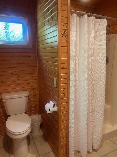 3199 S Lake Shore Dr, Bois Blanc, MI 49775 - full bath with toilet, tile patterned floors, wood walls, and a shower with curtain