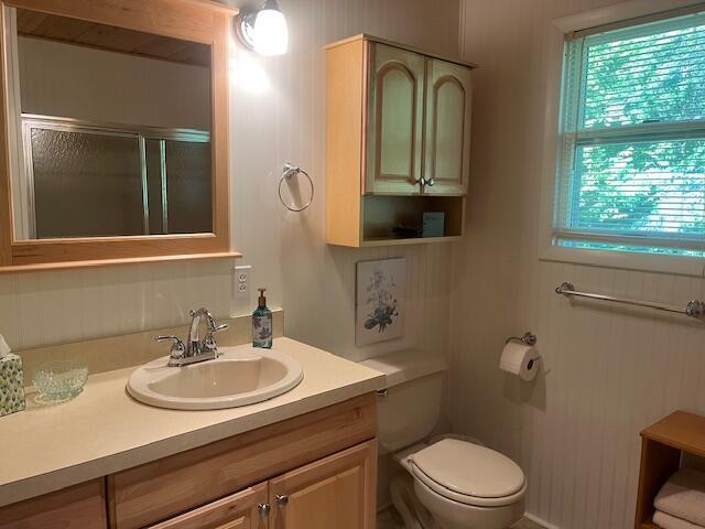 3199 S Lake Shore Dr, Bois Blanc, MI 49775 - full bathroom featuring toilet, vanity, and a shower with shower door