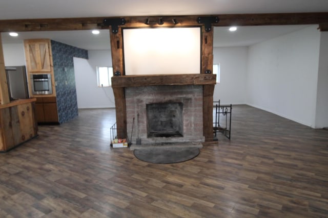 7844 Gilbert Trl, Grayling, MI 49738 - unfurnished living room featuring beam ceiling, dark wood finished floors, a fireplace with raised hearth, and a barn door