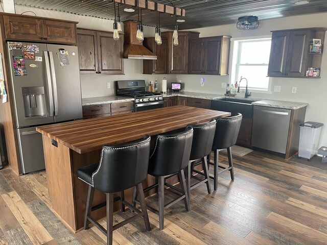 7557 Loop Rd, Posen, MI 49776 - kitchen featuring appliances with stainless steel finishes, butcher block countertops, wall chimney range hood, and wood finished floors