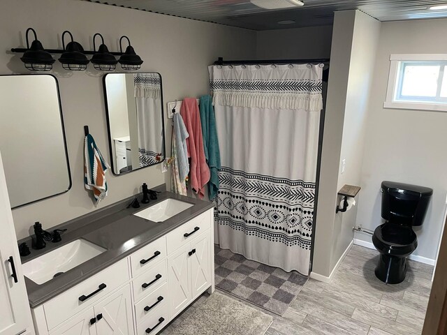 7557 Loop Rd, Posen, MI 49776 - bathroom featuring toilet, double vanity, baseboards, and a shower with shower curtain