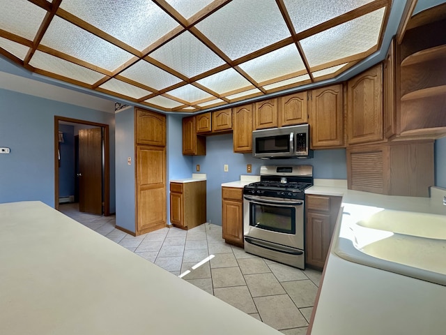 11030 S Stephan Bridge Rd, Roscommon, MI 48653 - kitchen with appliances with stainless steel finishes, light tile patterned floors, brown cabinets, and light countertops