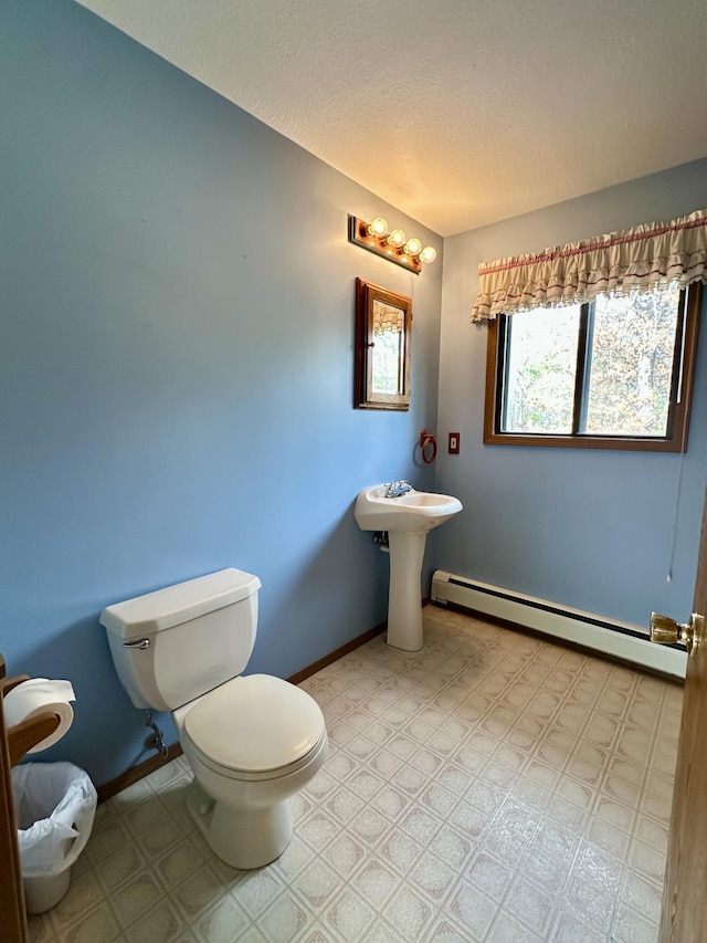 11030 S Stephan Bridge Rd, Roscommon, MI 48653 - bathroom featuring toilet, baseboard heating, a textured ceiling, tile patterned floors, and baseboards