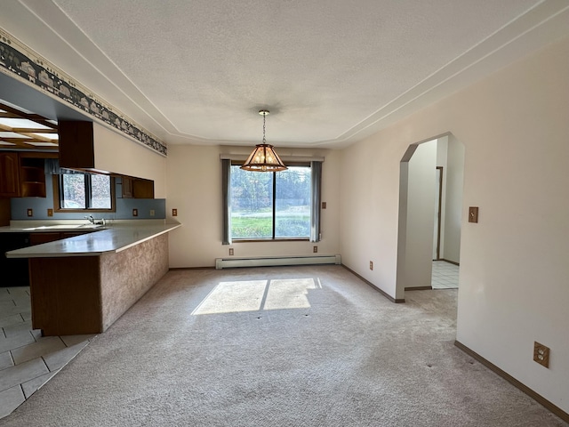 11030 S Stephan Bridge Rd, Roscommon, MI 48653 - kitchen featuring a baseboard heating unit, a peninsula, light countertops, light colored carpet, and arched walkways