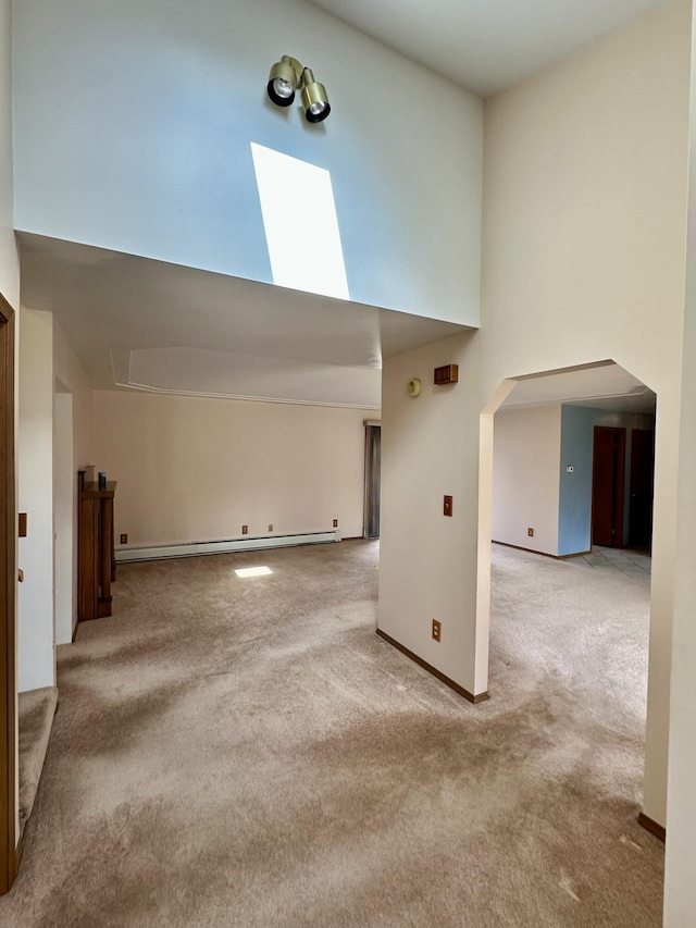 11030 S Stephan Bridge Rd, Roscommon, MI 48653 - empty room featuring carpet flooring, a towering ceiling, a baseboard radiator, a skylight, and attic access