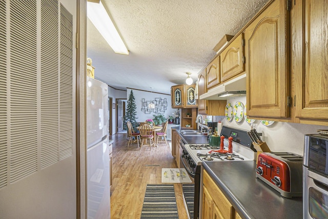398 Vale St, Cheboygan, MI 49721 - kitchen with gas stove, a heating unit, under cabinet range hood, a textured ceiling, and a sink