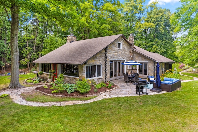 4423 Island View Dr, Gaylord, MI 49735 - back of house with stone siding, a chimney, an outdoor living space, and a patio