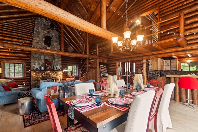 4423 Island View Dr, Gaylord, MI 49735 - dining room featuring log walls, hardwood / wood-style floors, high vaulted ceiling, plenty of natural light, and a chandelier