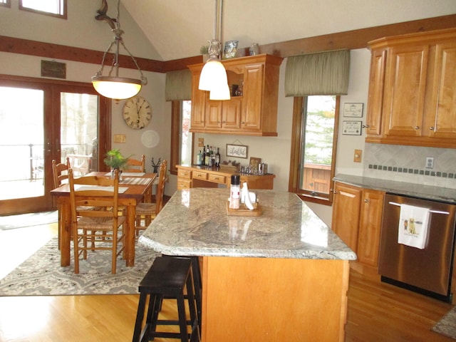 5622 Vacationland Dr, Lewiston, MI 49756 - kitchen featuring stainless steel dishwasher, light wood-style floors, a kitchen island, vaulted ceiling, and light stone counters