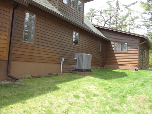5622 Vacationland Dr, Lewiston, MI 49756 - view of home's exterior featuring central AC unit, a lawn, and roof with shingles