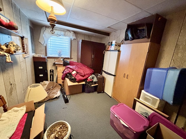 5356 Spruce Dr, Lewiston, MI 49756 - below grade area with freestanding refrigerator, carpet floors, wood walls, and a drop ceiling