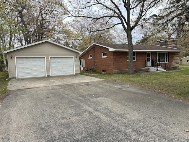 2323 Hobbs Dr, Alpena, MI 49707 - view of property exterior featuring an outbuilding, brick siding, a garage, a yard, and a chimney