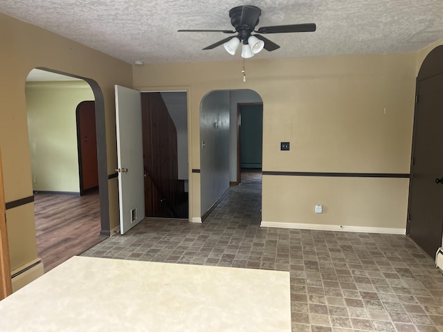 2323 Hobbs Dr, Alpena, MI 49707 - spare room with arched walkways, a ceiling fan, a textured ceiling, baseboard heating, and baseboards