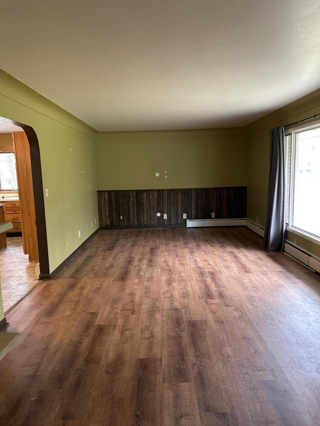 2323 Hobbs Dr, Alpena, MI 49707 - unfurnished living room featuring arched walkways, dark wood-style floors, and baseboards