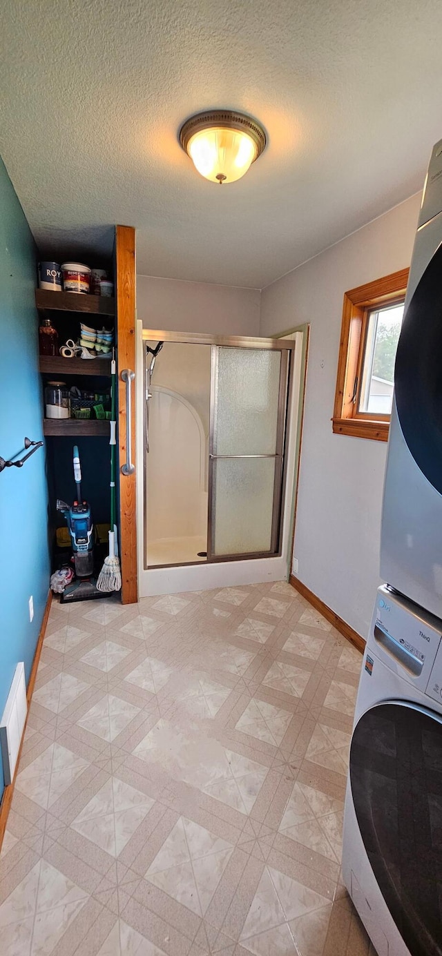 2460 Hamilton Rd, Alpena, MI 49707 - laundry room featuring estacked washer and dryer, baseboards, and a textured ceiling