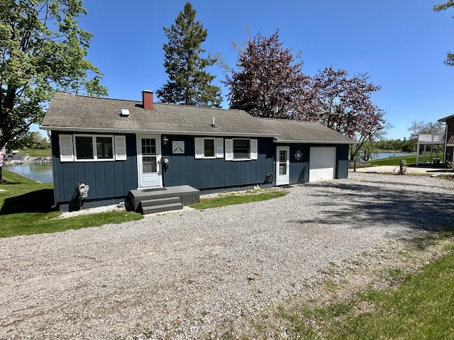 9452 M33, Cheboygan, MI 49721 - view of front of home with a garage, board and batten siding, driveway, a chimney, and a water view