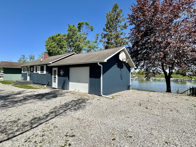 9452 M33, Cheboygan, MI 49721 - view of side of property with a garage, driveway, a water view, and a chimney