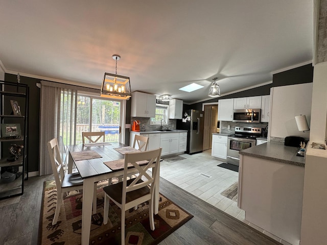1085 Five Lakes Rd, Gaylord, MI 49735 - dining area with ornamental molding, light wood-style flooring, a chandelier, and lofted ceiling