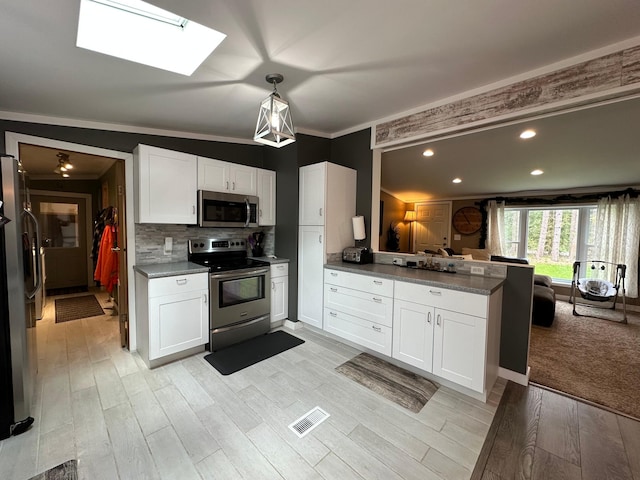 1085 Five Lakes Rd, Gaylord, MI 49735 - kitchen featuring stainless steel appliances, a peninsula, white cabinets, a skylight, and light wood-style floors
