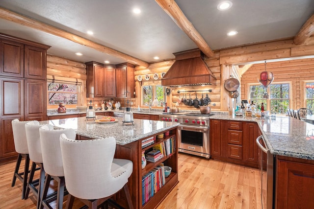 10924 E Grand Lake Rd, Presque Isle, MI 49777 - kitchen with rustic walls, designer range, premium range hood, beamed ceiling, and plenty of natural light