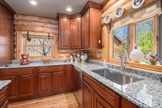 10924 E Grand Lake Rd, Presque Isle, MI 49777 - kitchen featuring a sink, stainless steel dishwasher, light wood-style flooring, light stone countertops, and rustic walls