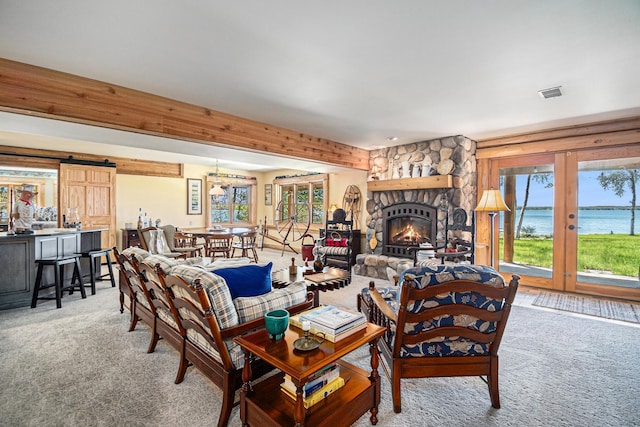 10924 E Grand Lake Rd, Presque Isle, MI 49777 - living area with carpet, french doors, a water view, a stone fireplace, and a barn door