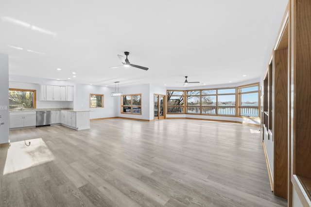 4348 W Lakeside Dr, West Branch, MI 48661 - unfurnished living room with recessed lighting, a water view, ceiling fan, light wood-style flooring, and a sink