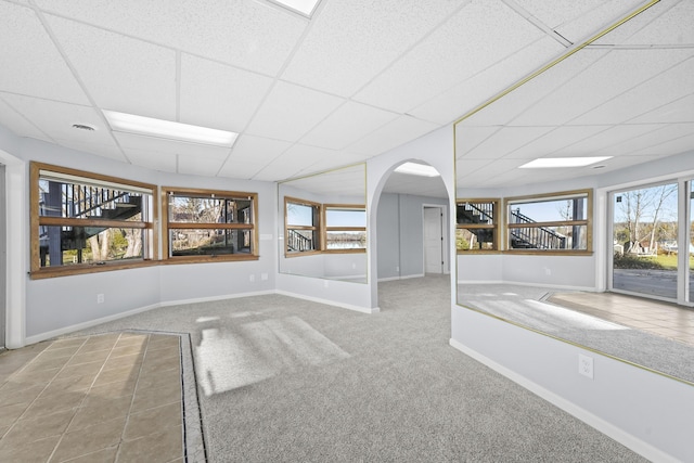 4348 W Lakeside Dr, West Branch, MI 48661 - empty room featuring a drop ceiling, baseboards, arched walkways, and carpet floors