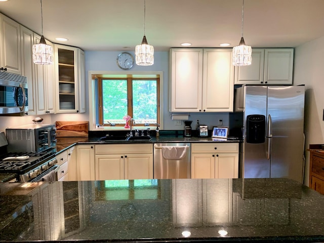 132 16th St, Prudenville, MI 48651 - kitchen with appliances with stainless steel finishes, a sink, a chandelier, dark stone countertops, and glass insert cabinets