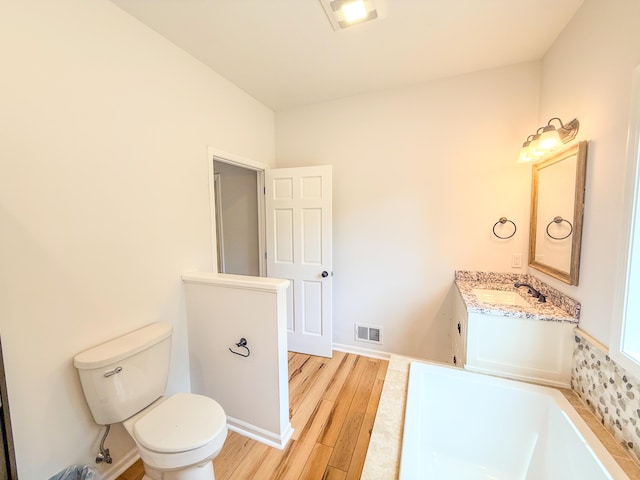 116 No Wake Ct, Houghton Lake, MI 48629 - full bathroom with toilet, wood finished floors, a garden tub, vanity, and baseboards