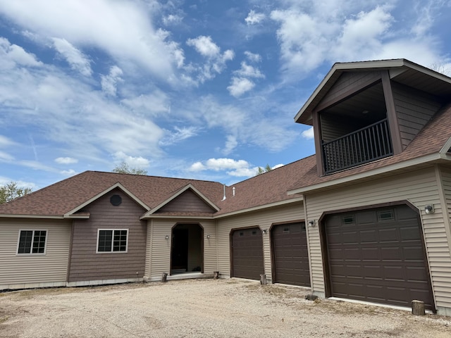 116 No Wake Ct, Houghton Lake, MI 48629 - view of front facade with roof with shingles, a balcony, dirt driveway, and a garage