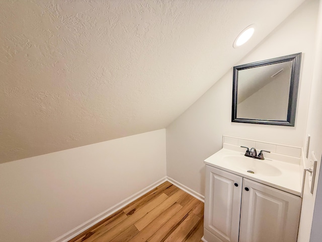 116 No Wake Ct, Houghton Lake, MI 48629 - bathroom featuring vaulted ceiling, a textured ceiling, wood finished floors, vanity, and baseboards