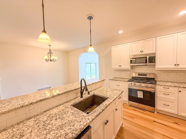 116 No Wake Ct, Houghton Lake, MI 48629 - kitchen featuring appliances with stainless steel finishes, a sink, light wood-style flooring, tasteful backsplash, and white cabinets