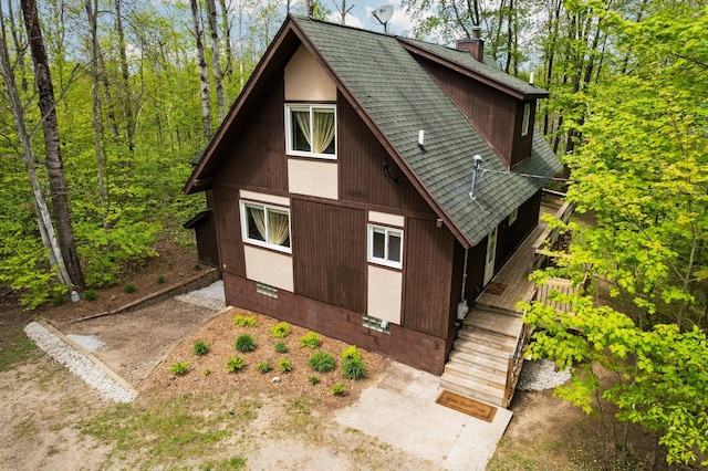 6192 Wilderness Dr, Mancelona, MI 49659 - view of side of home featuring a shingled roof and a chimney