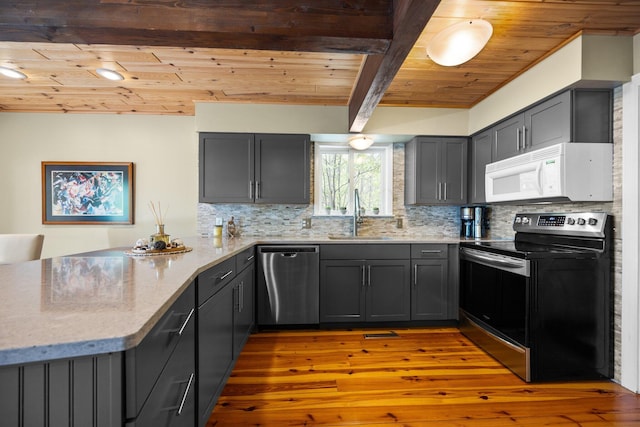 6192 Wilderness Dr, Mancelona, MI 49659 - kitchen with appliances with stainless steel finishes, a sink, a peninsula, wooden ceiling with exposed beams, and backsplash