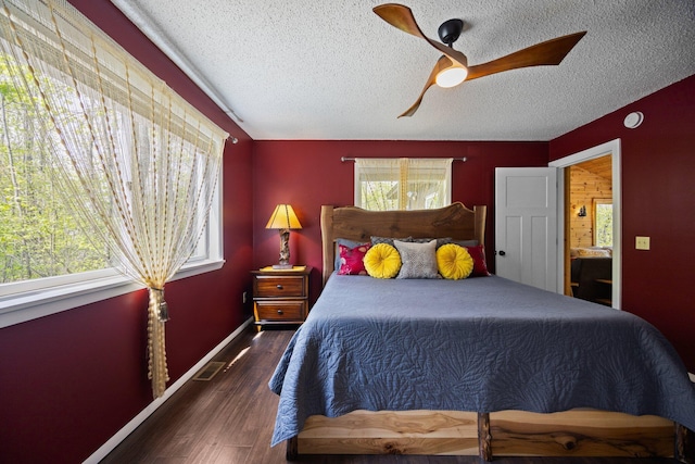 6192 Wilderness Dr, Mancelona, MI 49659 - bedroom with a textured ceiling, multiple windows, wood finished floors, ceiling fan, and baseboards