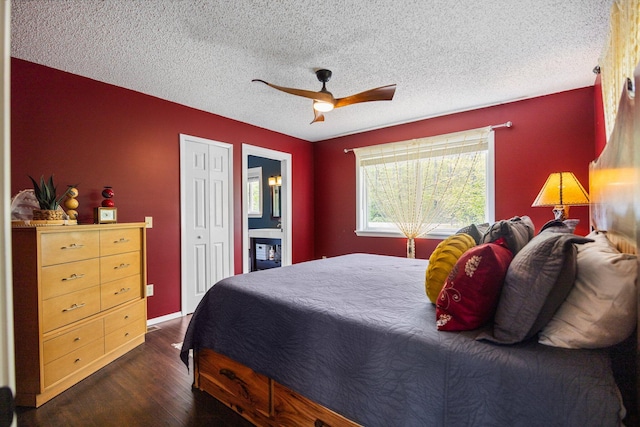 6192 Wilderness Dr, Mancelona, MI 49659 - bedroom featuring dark wood-style floors, a textured ceiling, ceiling fan, a closet, and connected bathroom