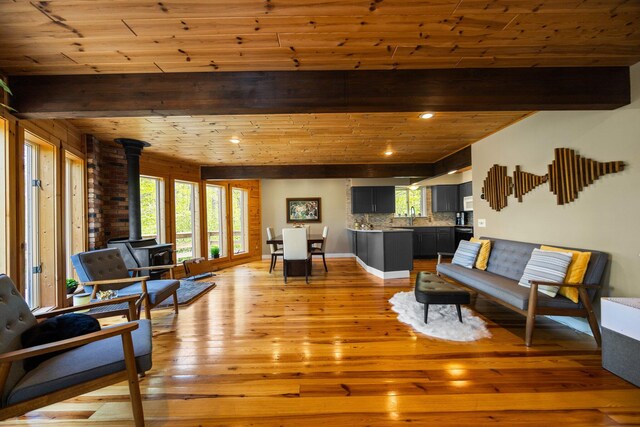 6192 Wilderness Dr, Mancelona, MI 49659 - living area featuring a wood stove, light wood-style floors, wooden ceiling with exposed beams, and recessed lighting