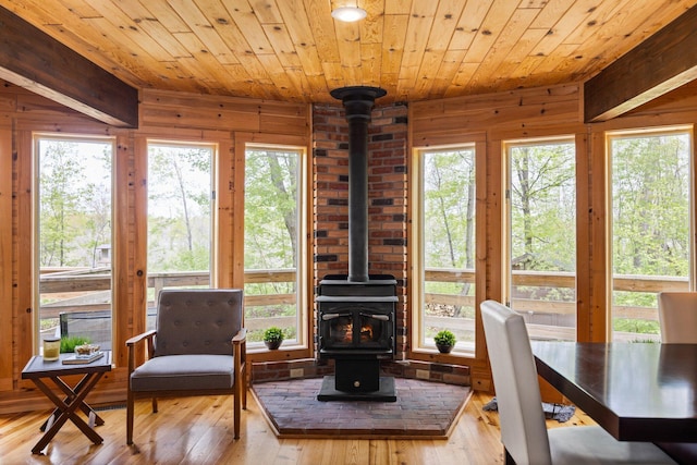 6192 Wilderness Dr, Mancelona, MI 49659 - dining space featuring a wood stove, wood ceiling, plenty of natural light, wood walls, and hardwood / wood-style floors