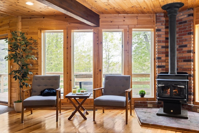 6192 Wilderness Dr, Mancelona, MI 49659 - sitting room featuring a wood stove, wood ceiling, wood walls, wood-type flooring, and healthy amount of natural light