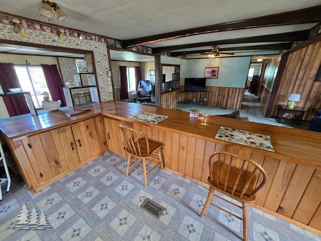 3557 Penn Rd, Lewiston, MI 49756 - kitchen with wooden walls, ceiling fan, beam ceiling, a wainscoted wall, and wallpapered walls
