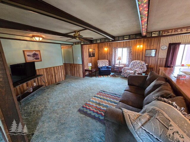 3557 Penn Rd, Lewiston, MI 49756 - living room with carpet, healthy amount of natural light, beam ceiling, wooden walls, and a ceiling fan