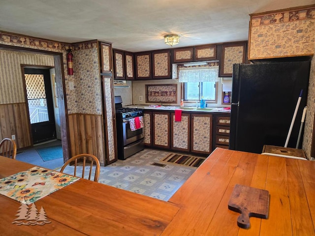 3557 Penn Rd, Lewiston, MI 49756 - kitchen featuring stainless steel gas range, freestanding refrigerator, wallpapered walls, wainscoting, and ventilation hood