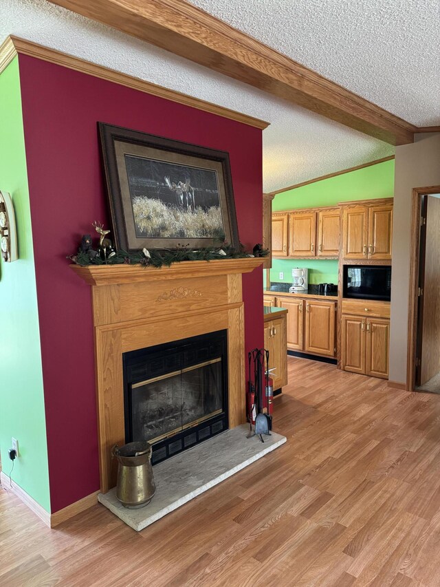 1154 M-72 W, Barton City, MI 48705 - living area with a textured ceiling, beamed ceiling, light wood-type flooring, a glass covered fireplace, and ornamental molding