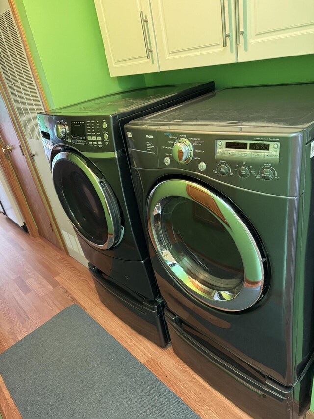 1154 M-72 W, Barton City, MI 48705 - laundry area with washing machine and clothes dryer, cabinet space, and wood finished floors