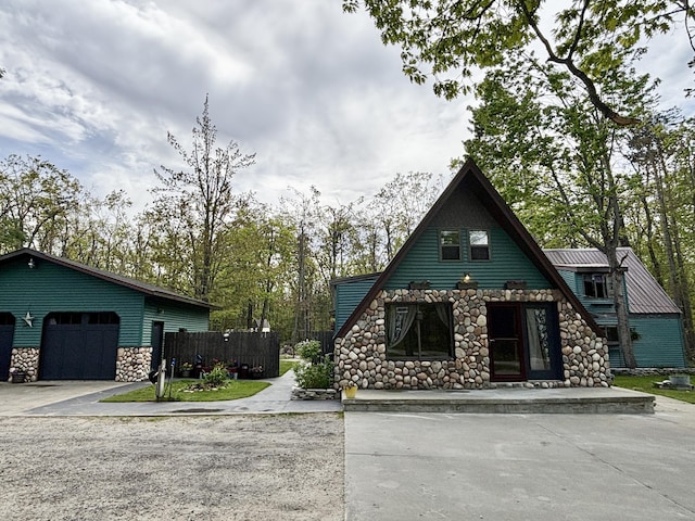 3334 Pleasant View Dr, Lewiston, MI 49756 - a-frame style home with stone siding, a garage, concrete driveway, and an outdoor structure