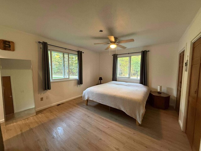 116 1st St, Hubbard Lake, MI 49747 - bedroom featuring multiple windows, wood finished floors, baseboards, and a ceiling fan