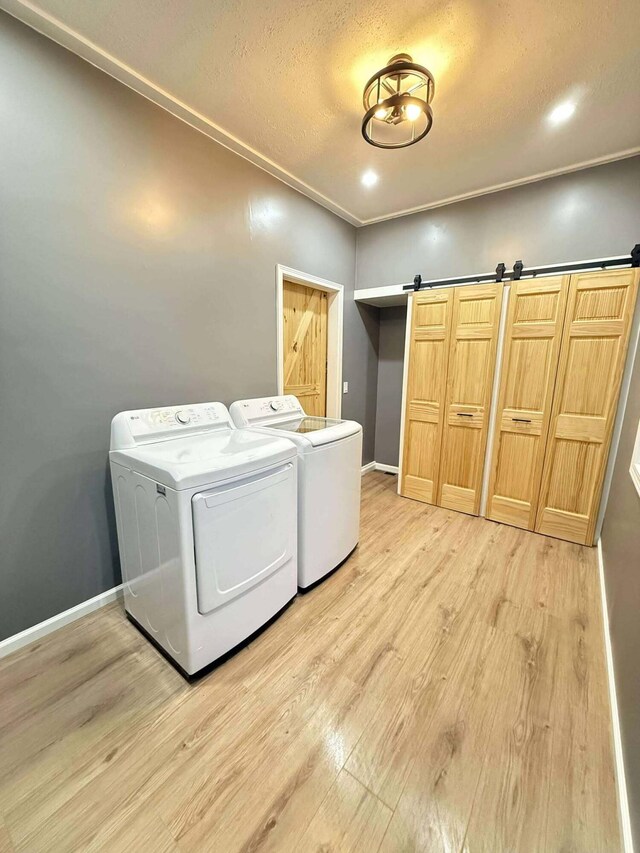 116 1st St, Hubbard Lake, MI 49747 - laundry room featuring washer and clothes dryer, light wood-type flooring, baseboards, a barn door, and recessed lighting